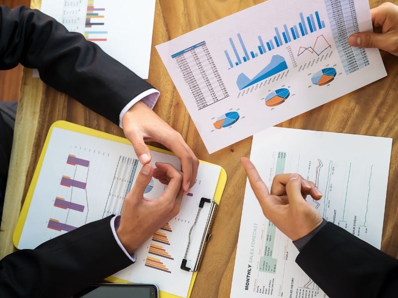 due mani sulla scrivania congiunte e due mani indicano dei grafici