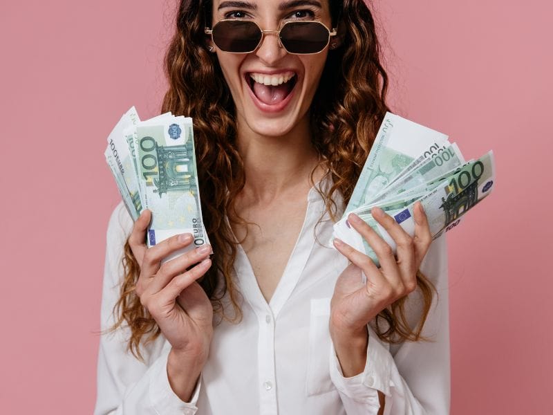 ragazza ride con banconote da 100 euro in mano
