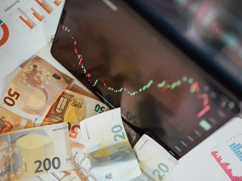 banconote euro sulla scrivania con computer che mostra mercato azionario