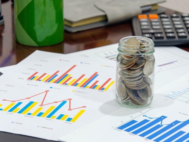 grafici di investimenti finanziari con un barattolo di monete